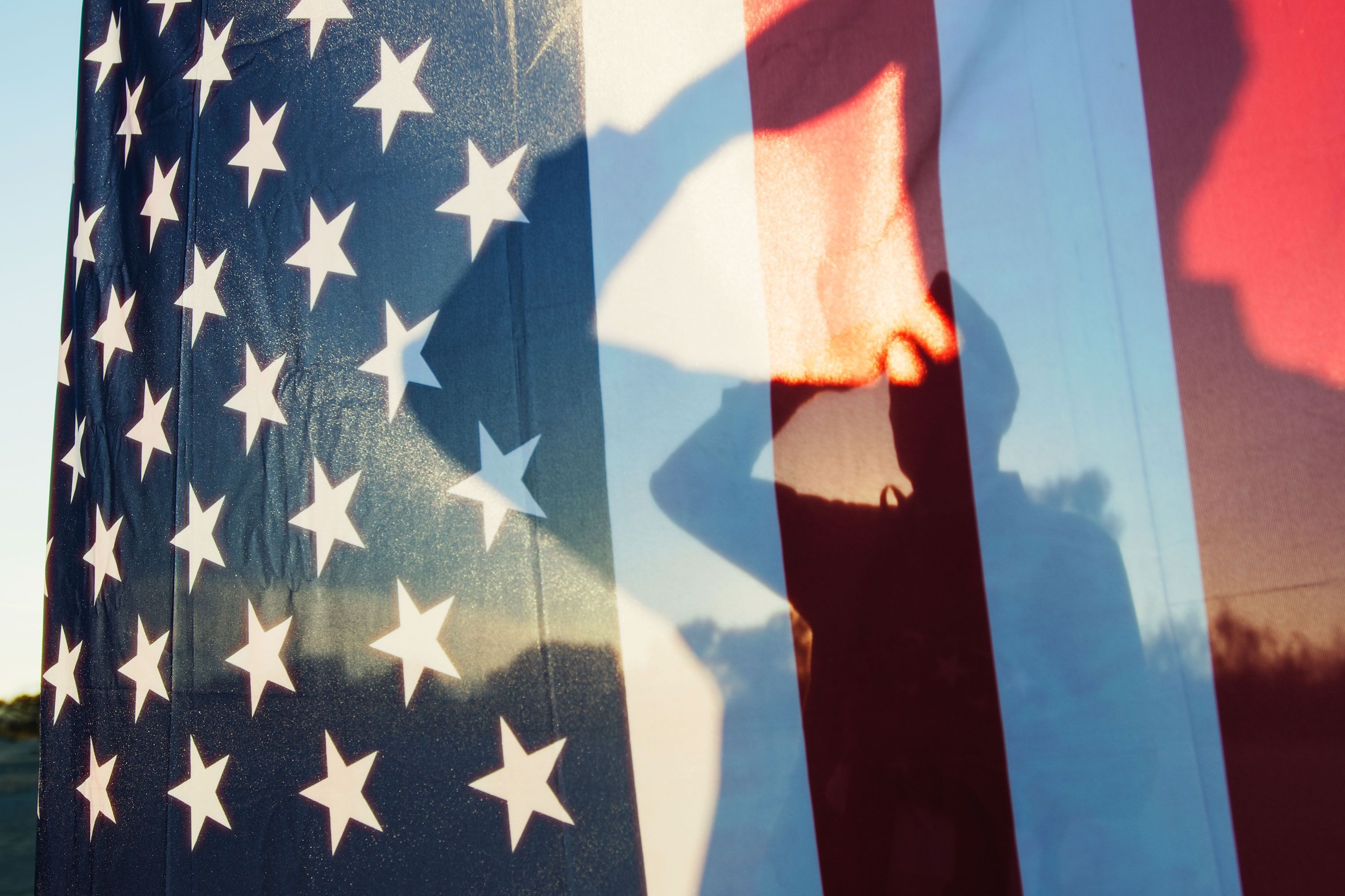 A shadow of a man saluting the American flag.