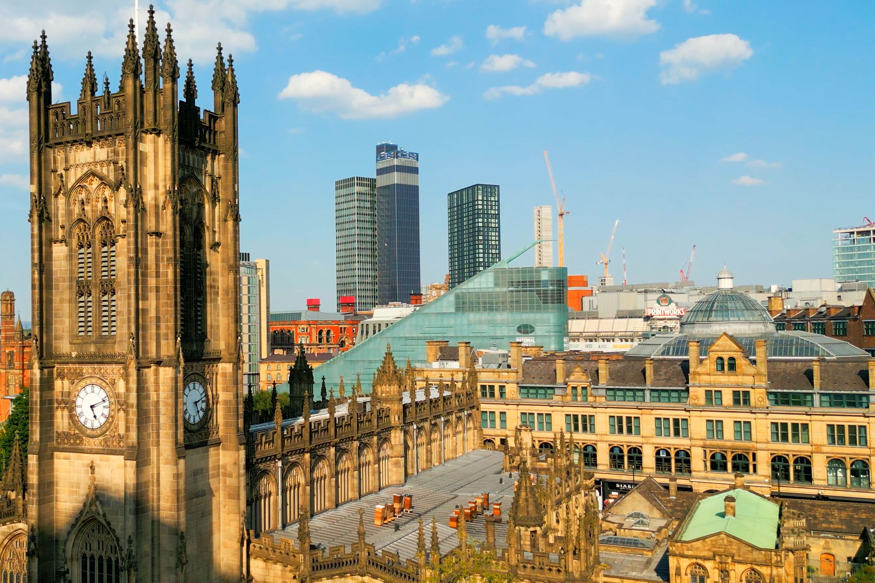 A Gothic clock tower and historic buildings with a modern city skyline in the background.