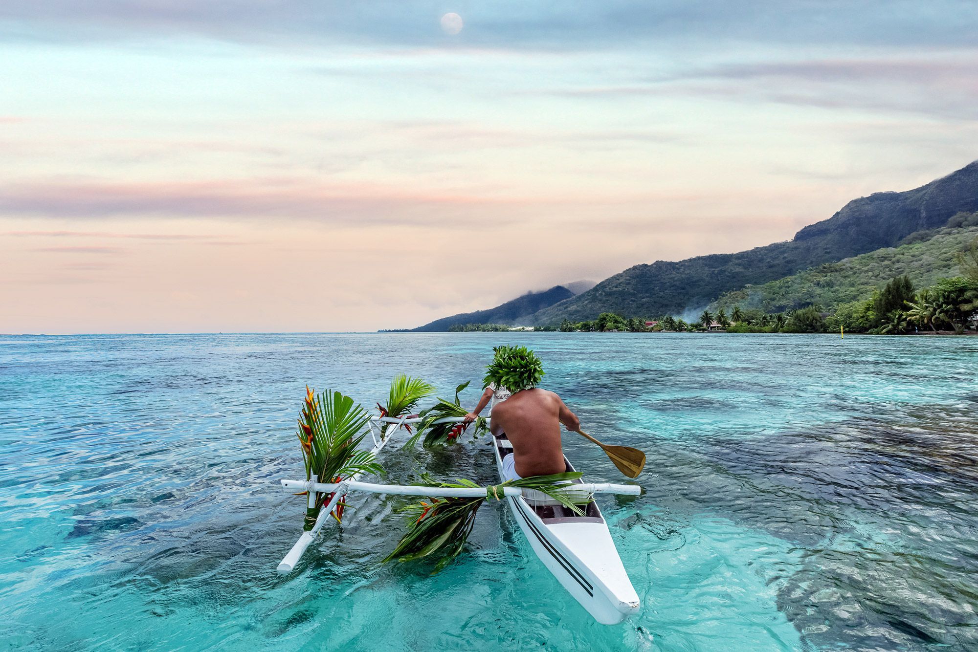A man on a canoe in the ocean of Mo'orea, Polynesia.