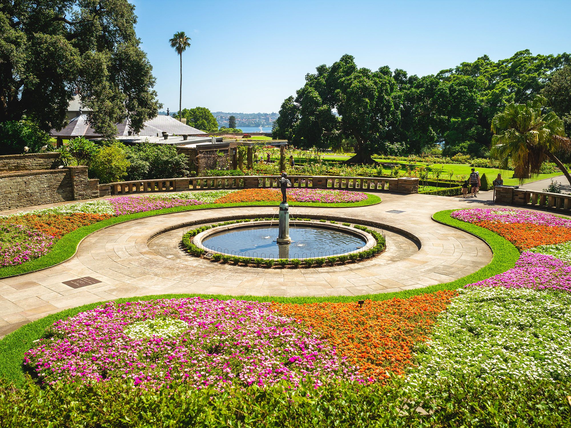 Colorful flowers in a triangle pattern around a circular pathway and a fountain in the middle.