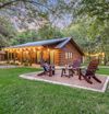A log cabin Vrbo with adirondacks in the yard, in Wimberley, Texas