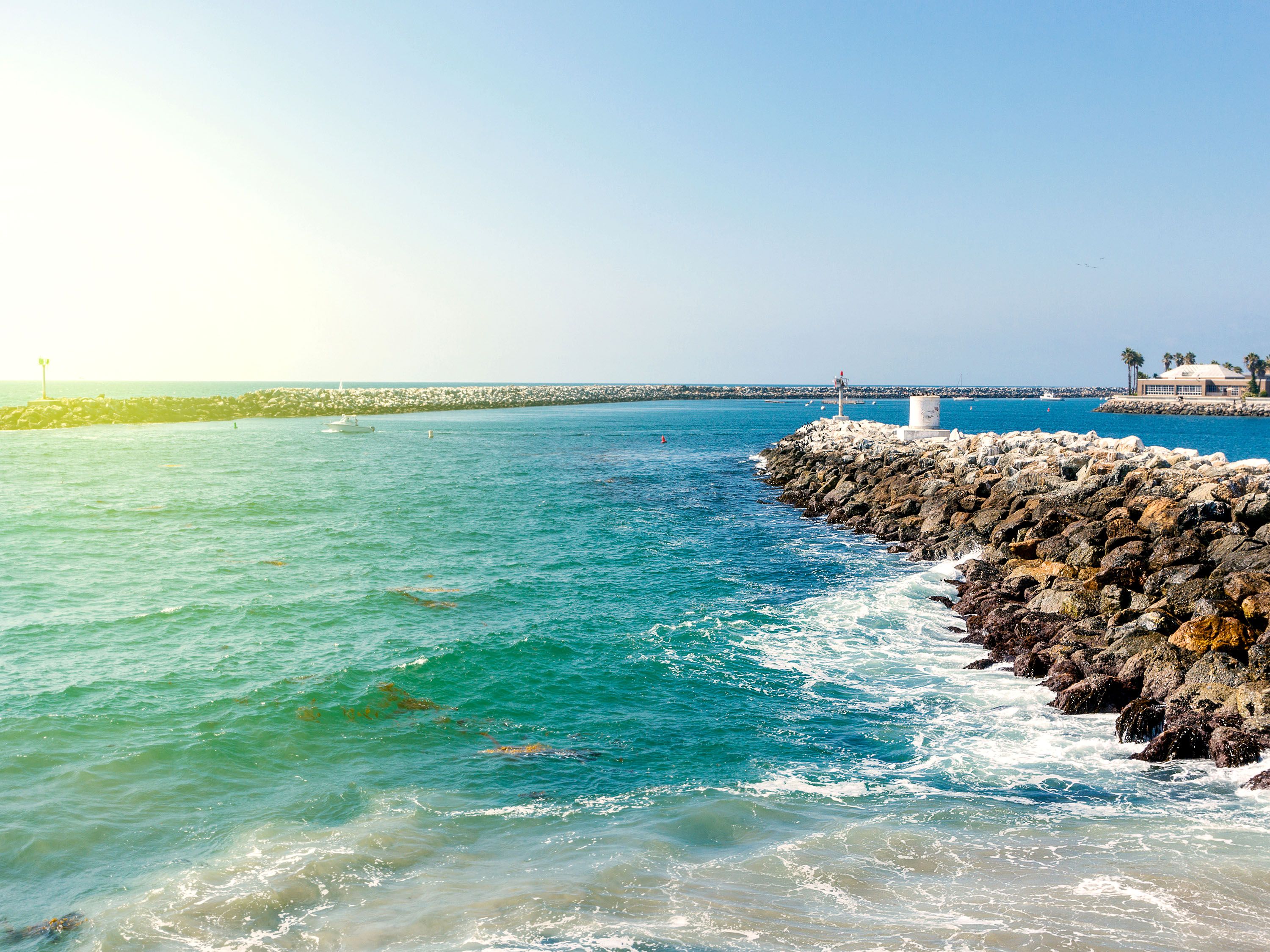 Stone breakwall into blue ocean water.