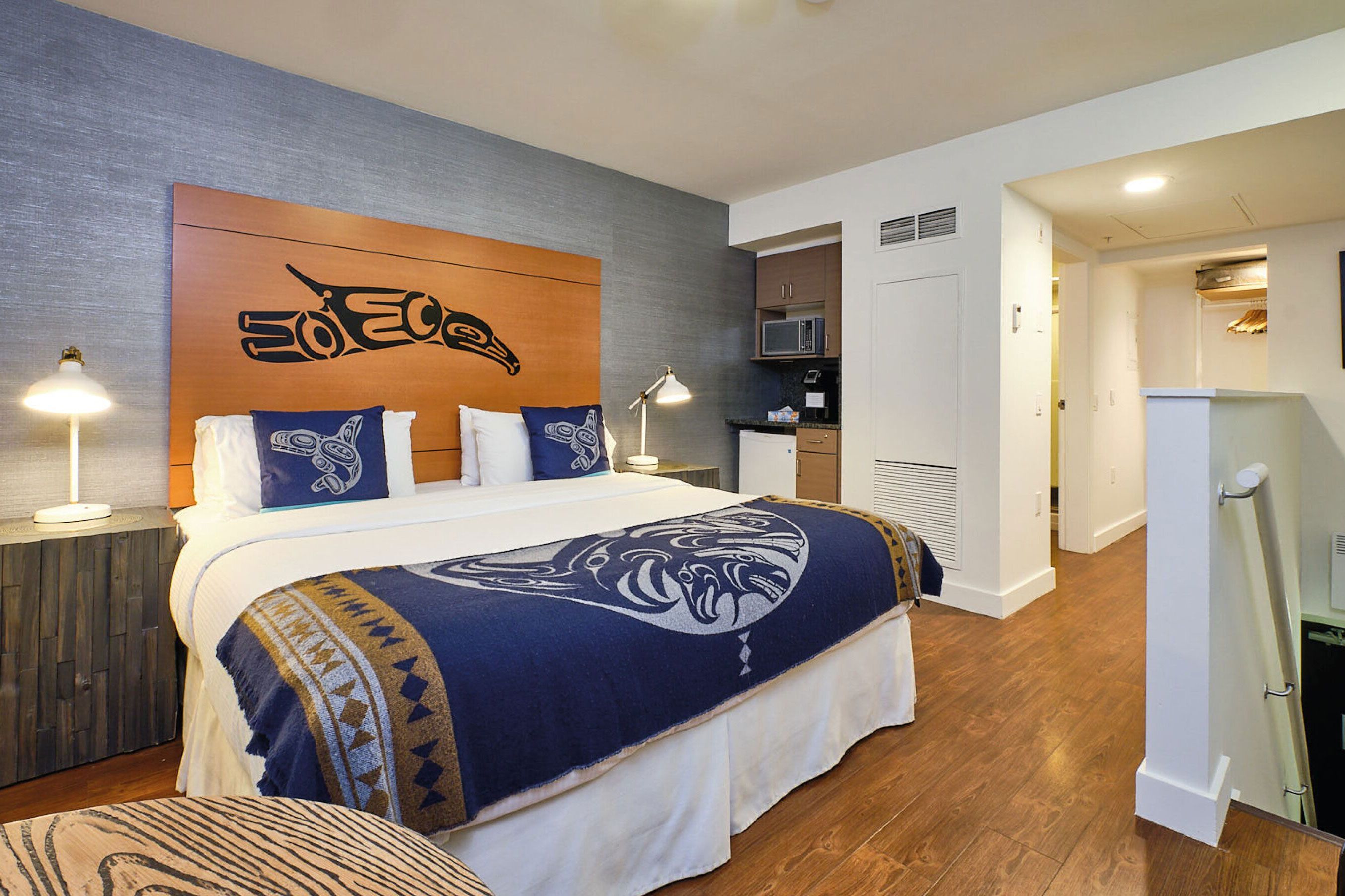 Pacific Northwest indian designs in a room with a bed and mini kitchen with wooden floors.