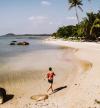 A traveler walks along the sandy shores of Koh Samui