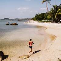 A traveler walks along the sandy shores of Koh Samui