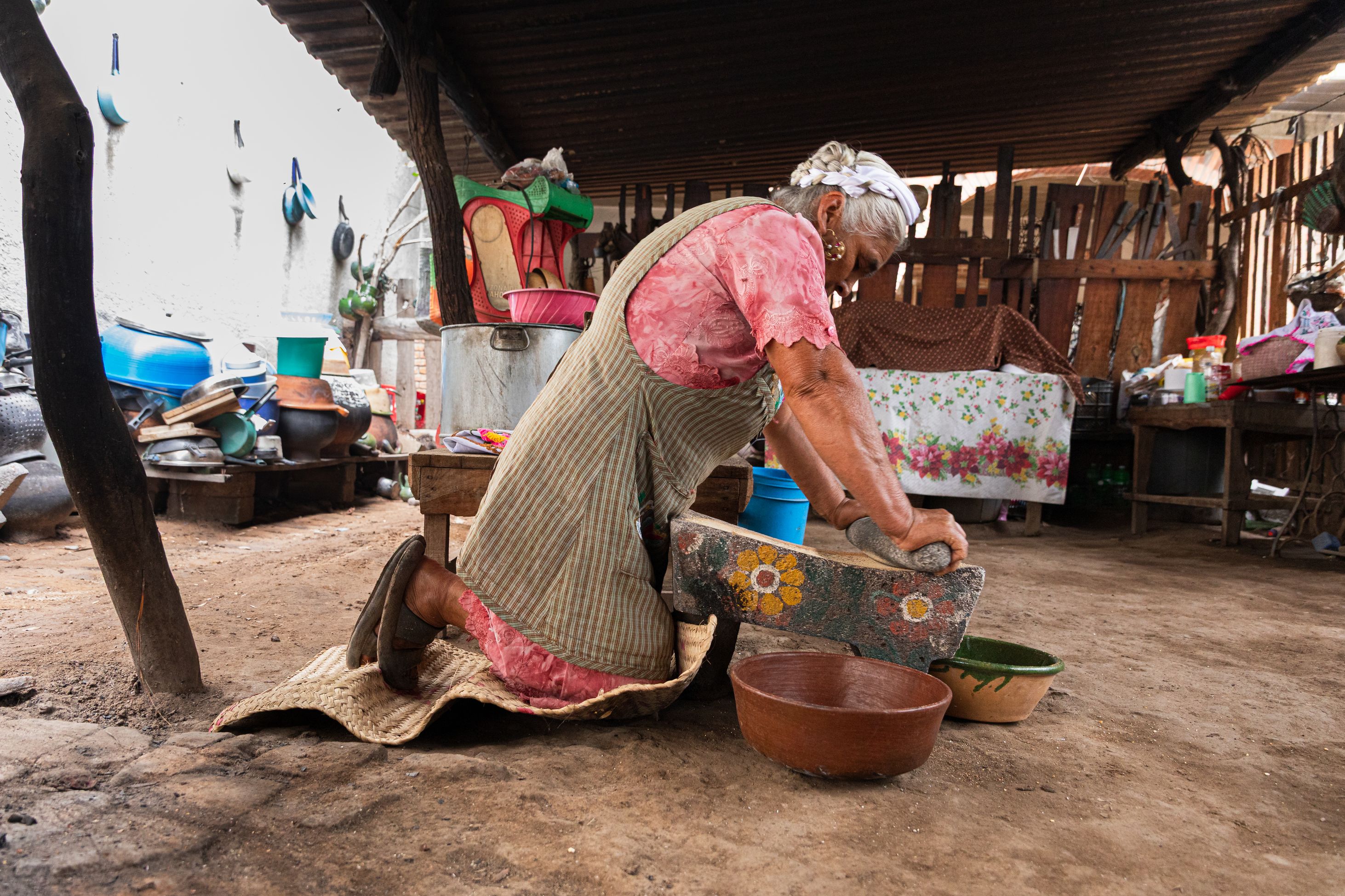 Woman using a metate stone in a courtyard in Oaxaca, Mexico