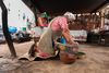 Woman using a metate stone in a courtyard in Oaxaca, Mexico