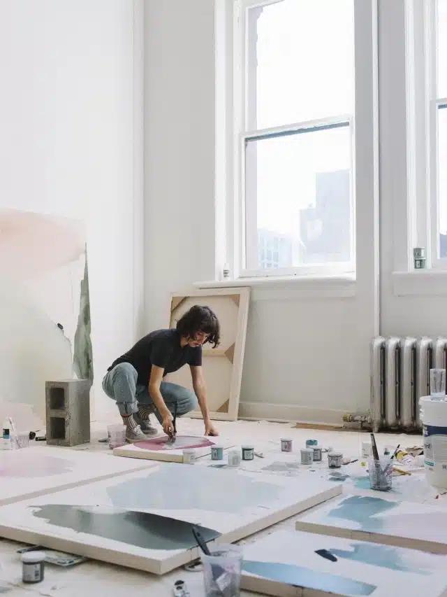 Artist Meghan Bustard at work painting large canvases in a light filled room