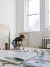 Artist Meghan Bustard at work painting large canvases in a light filled room
