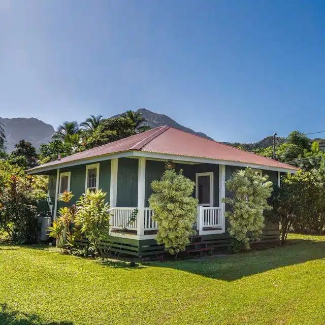 A petite bungalow Vrbo with sloping red roof and deck, set in a garden