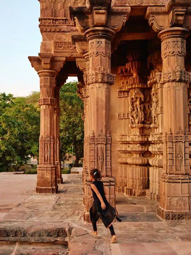 A young girl runs barefoot among pillars of an ancient building at Mandore Garden, Rajasthan, India