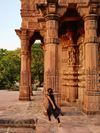 A young girl runs barefoot among pillars of an ancient building at Mandore Garden, Rajasthan, India