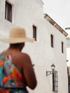 A woman in a straw hat walks past a whitewashed colonial building in Santo Domingo; visit in December through April for the best weather