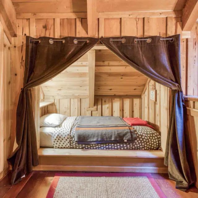 Curtains drawn back to reveal a bed in a nook in a Vrbo in Vermont