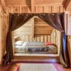 Curtains drawn back to reveal a bed in a nook in a Vrbo in Vermont