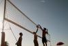 People play beach volleyball on a sunny day