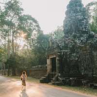 A female cyclist rides past the entrance to an ancient stone temple