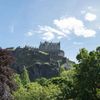 Edinburgh Castle as seen from below, with trees in the foreground and a bright blue sky beyond