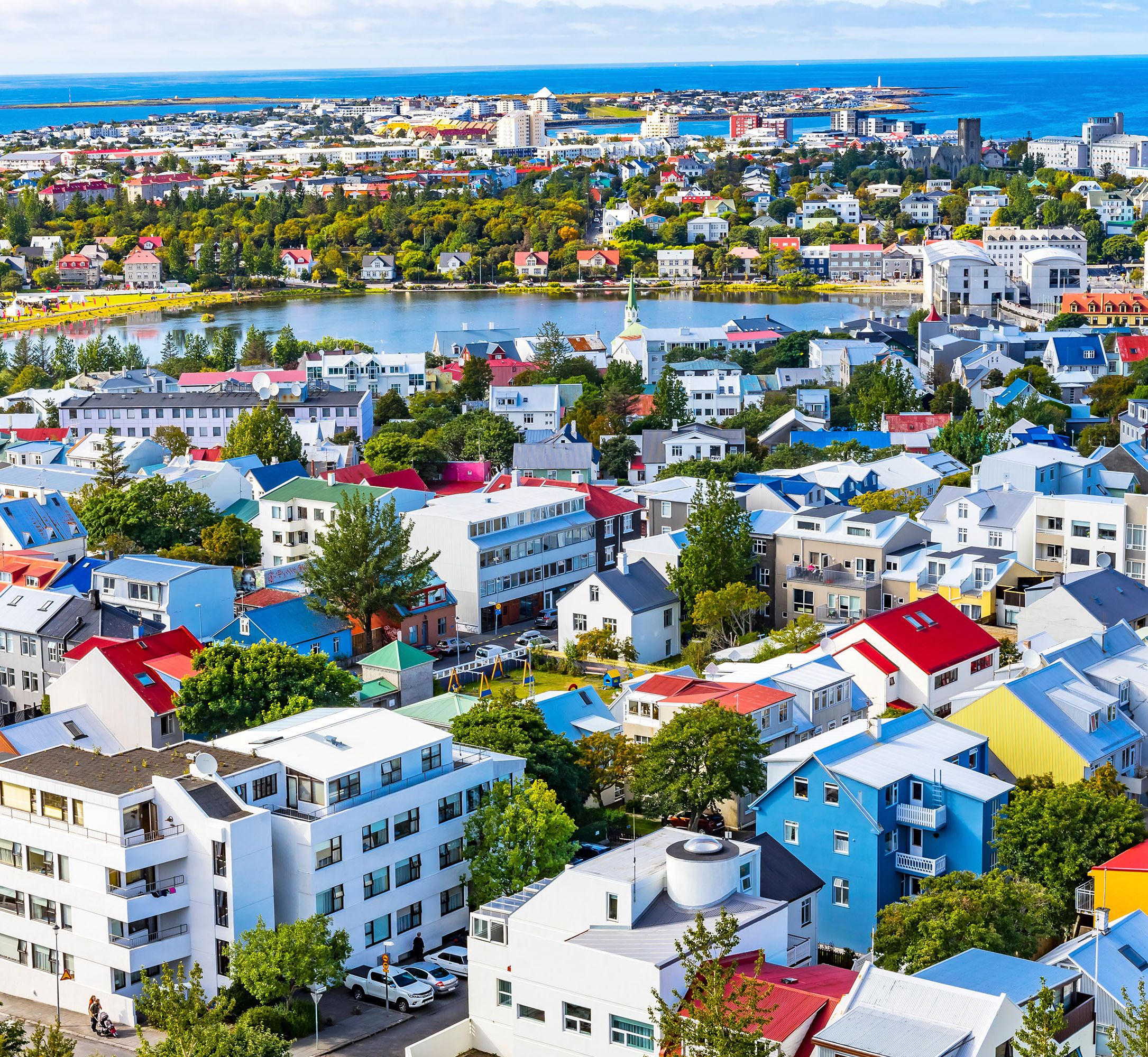 Aerial view of church and city center overlooking water and white-capped mountains.