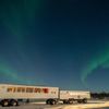 The northern lights seen above Dan’s Diner, Manitoba, Canada, two carriages on wheels with warm light glowing inside