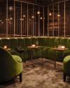 The green velvet sofas and rose gold, mirror-lined walls in the bar at The Londoner hotel in London, U.K.