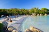 People on a white sandy beach surrounded by trees.