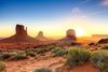 A cluster of sandstone buttes in a desert reaching out into the sky at sunset.