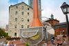 Contemporary metal and copper sculpture stands near restored brick buildings in Toronto’s Distillery District