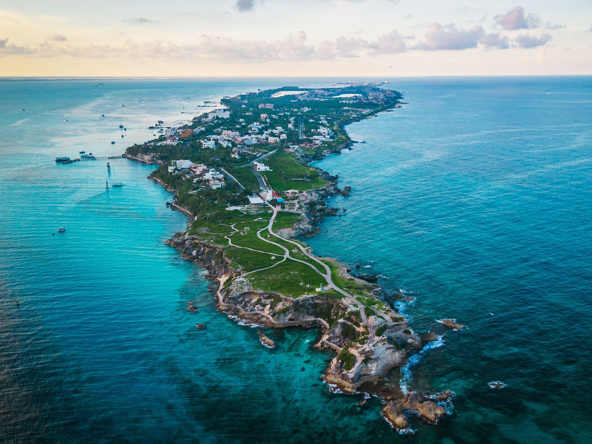 Aerial view of a thin island in the middle of the ocean during sunset.