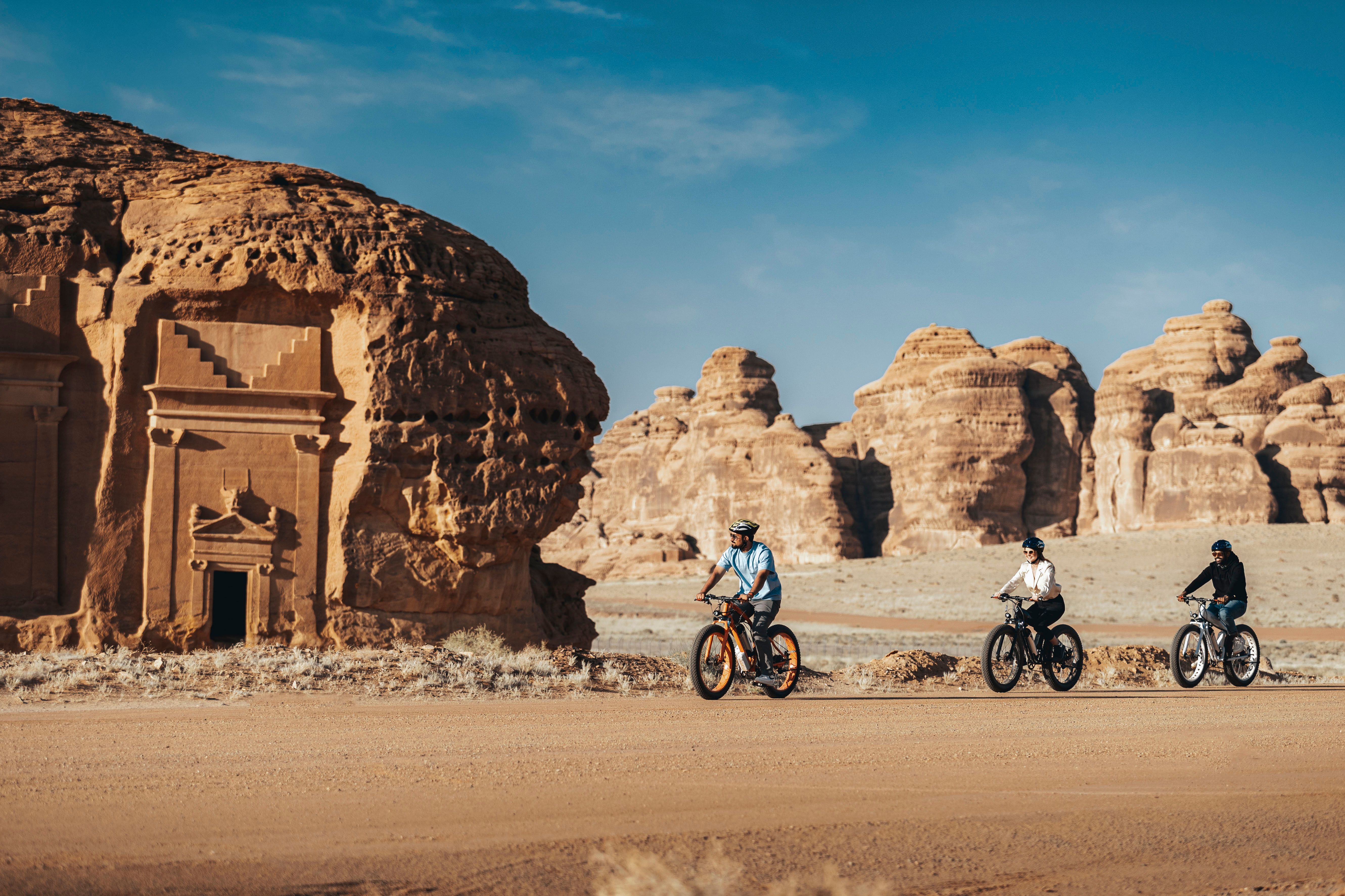 Cycling past ancient rock-cut facades of Hegra