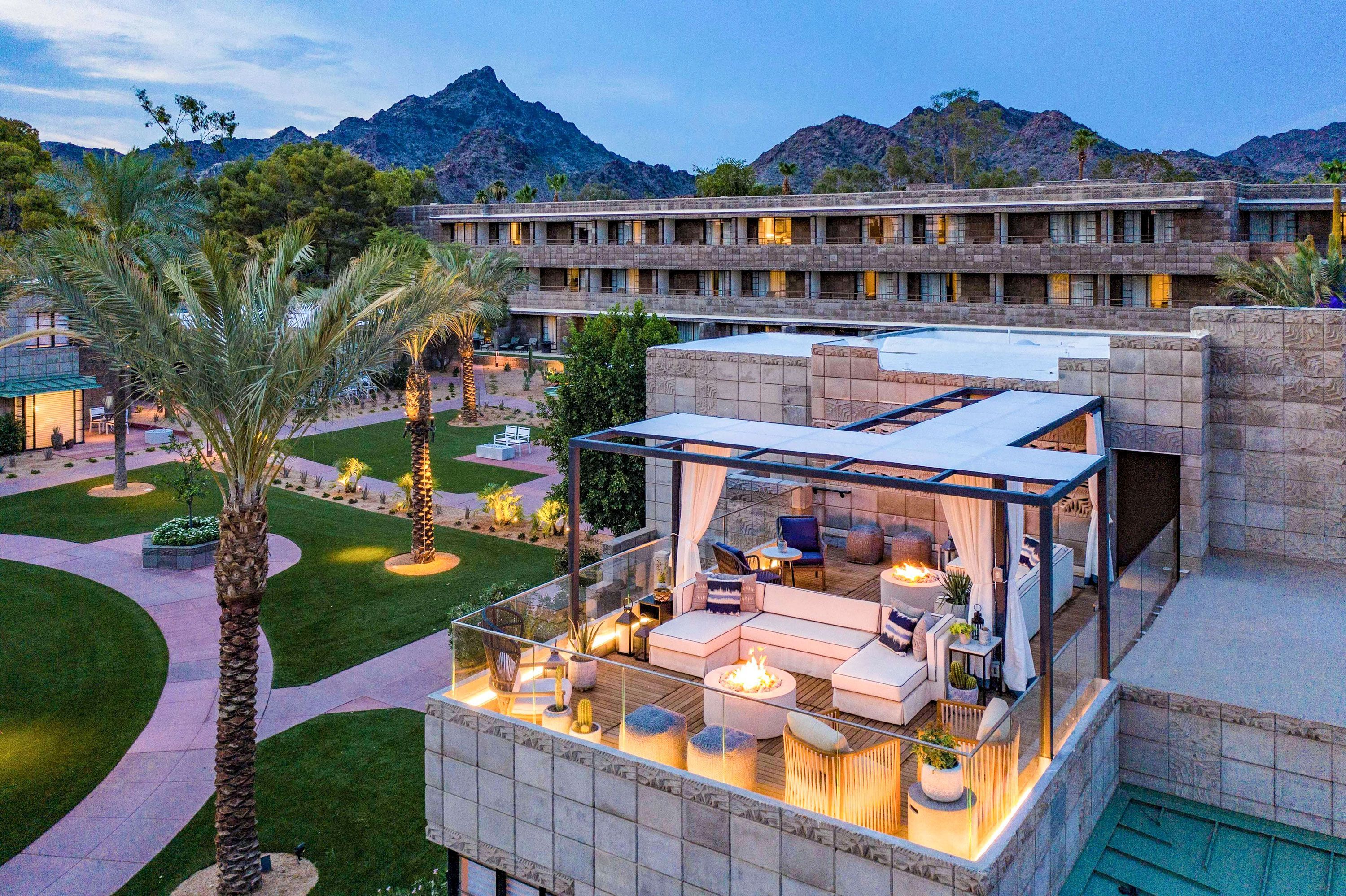 Slightly aerial view of Art Deco coumpound at sunset with palm trees, walkways and outdoor lounge area with firepits.