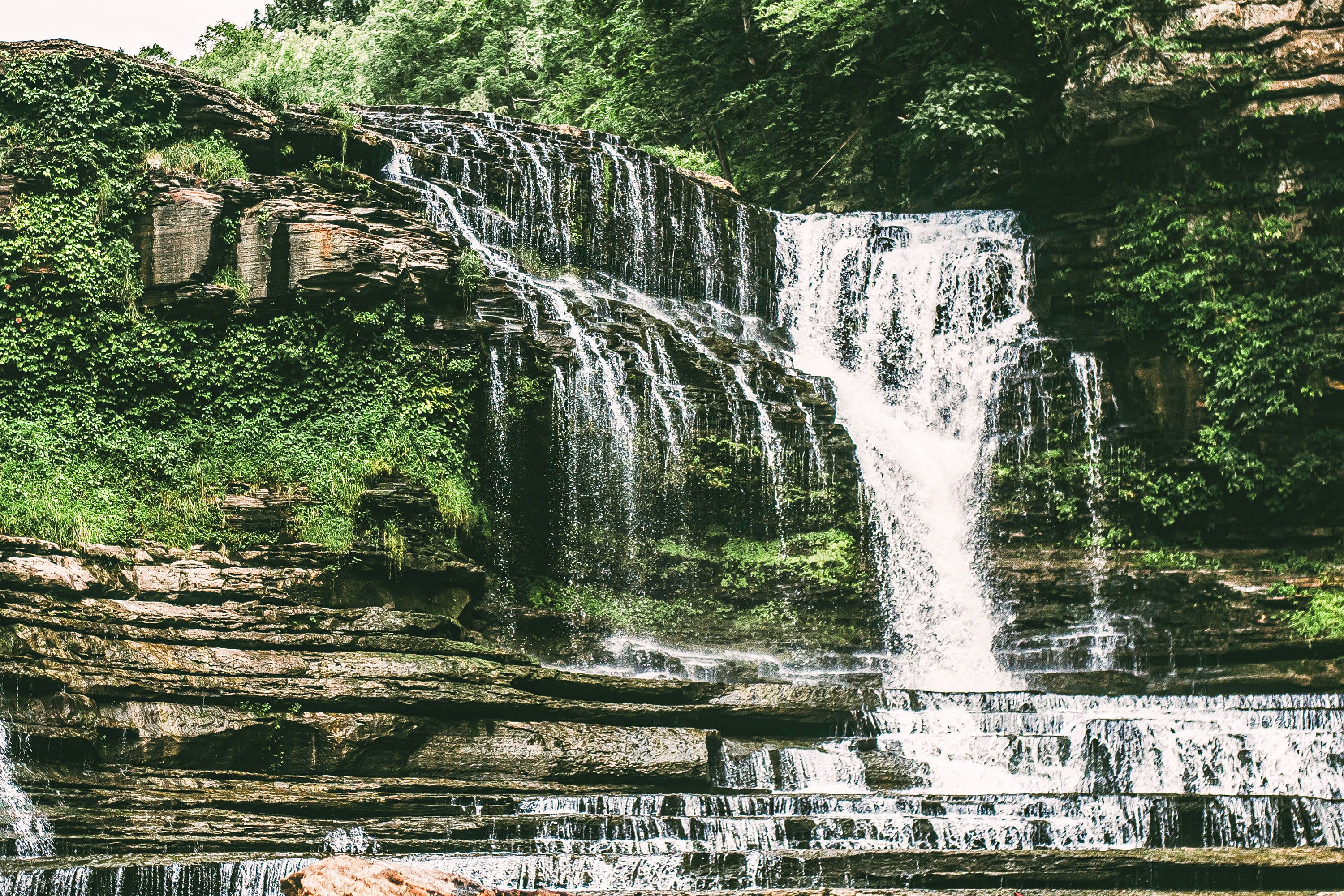 Multiple waterfalls with lush vegetation.