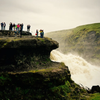 Travelers look out over a waterfall in Iceland