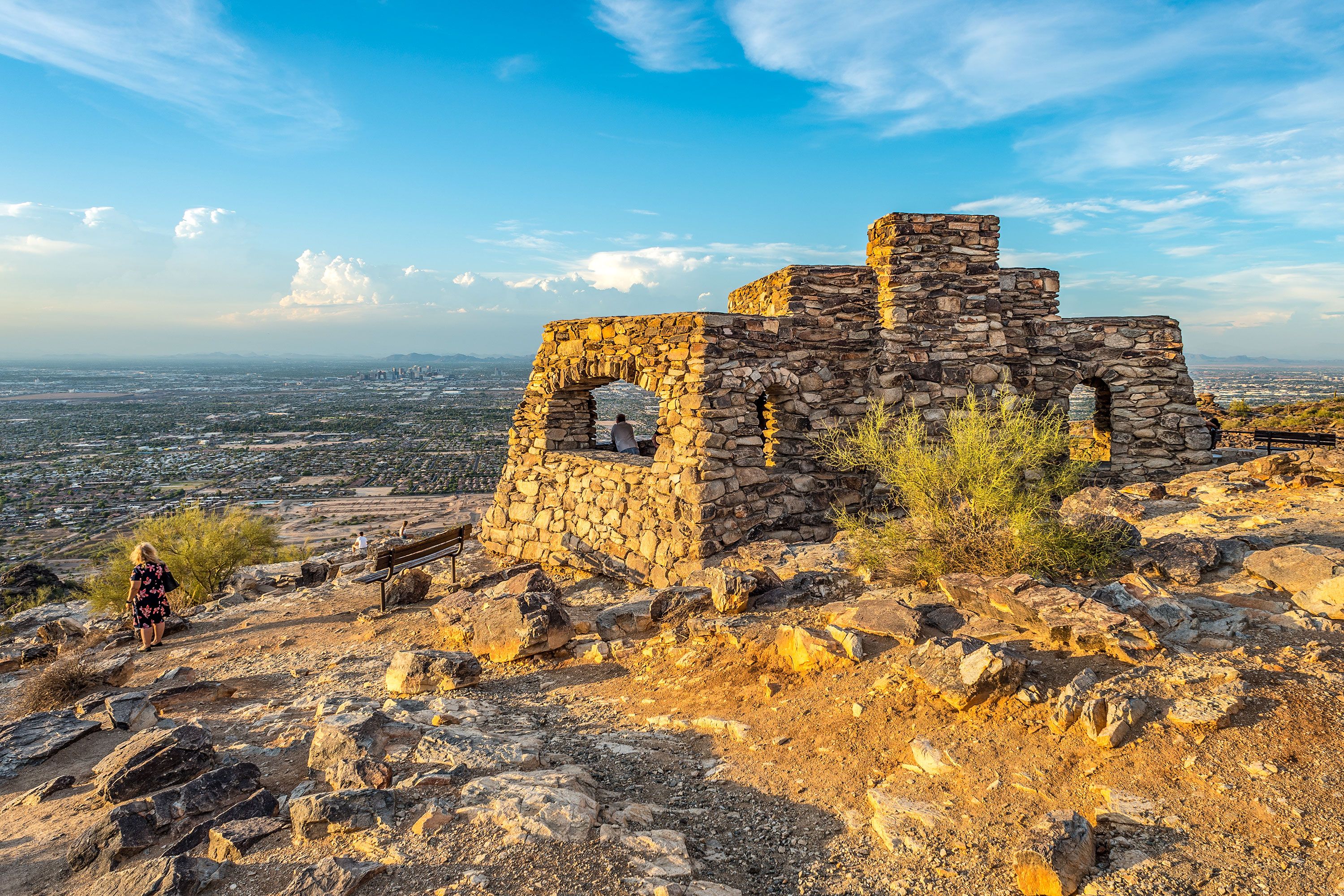 A crude stone structure set on a hill with a view over a plain under a hazy sky.