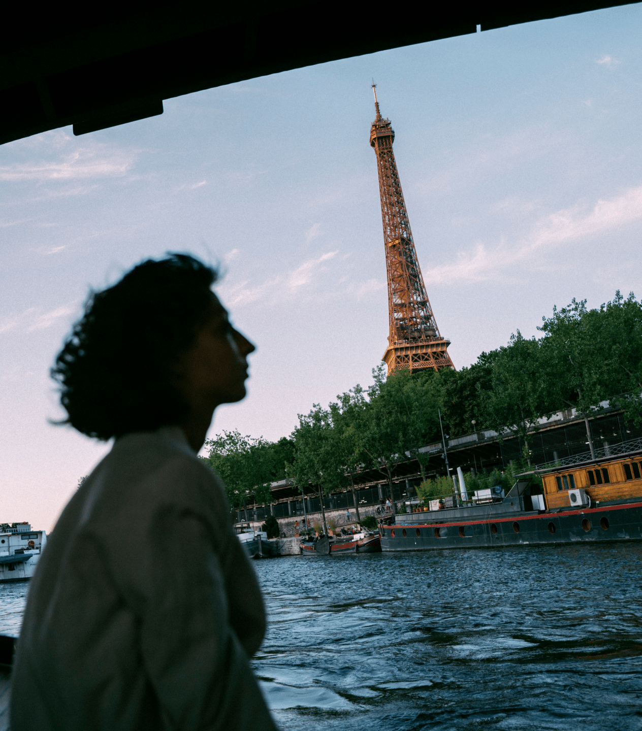 A silhouetted woman on a boat on the Seine, the Eiffel Tower visible behind her