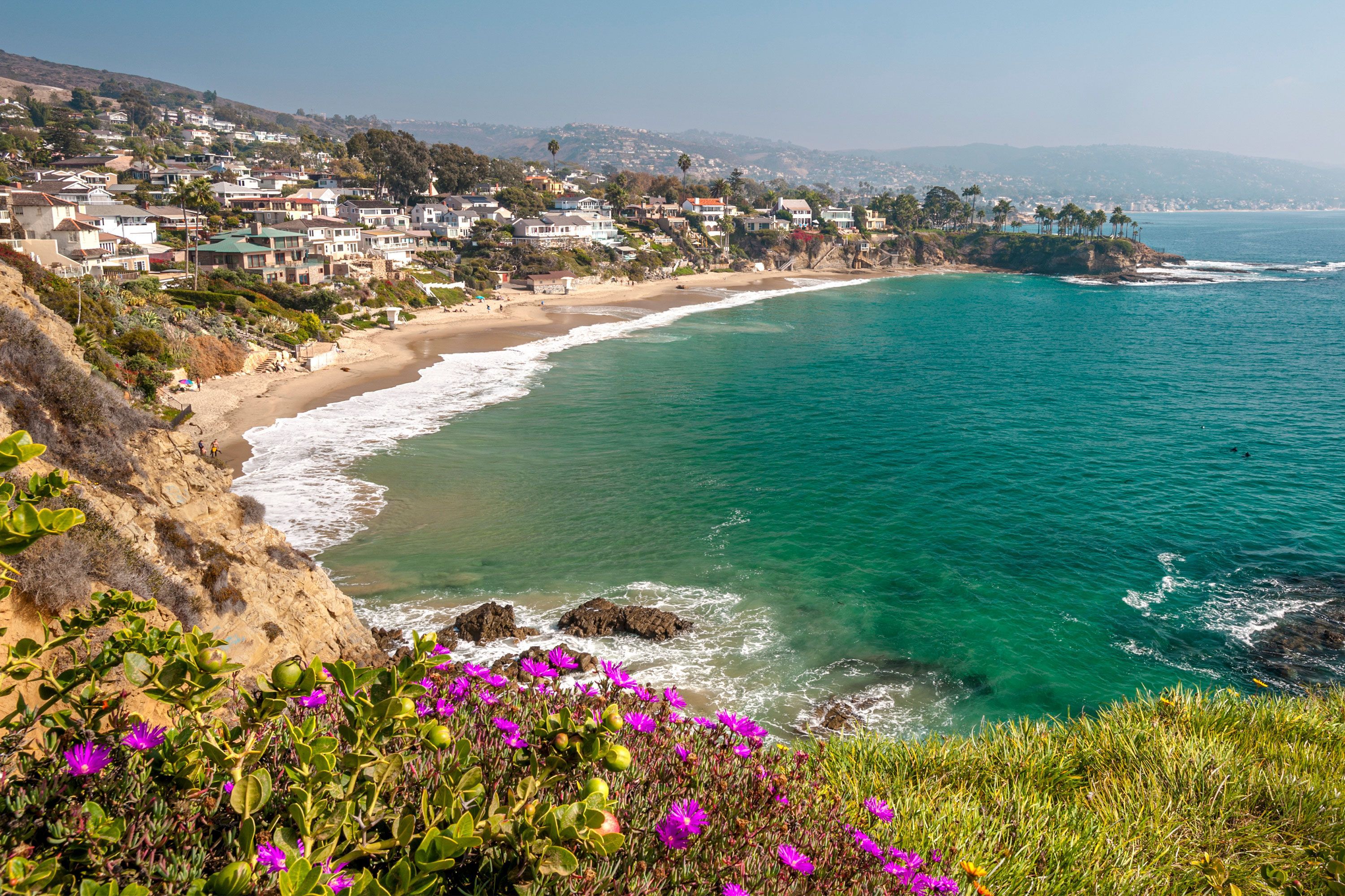 A top-down view of Shaw’s Cove in Laguna Beach, showing the shoreline, rocks, and turquoise ocean from a high cliff overlook.