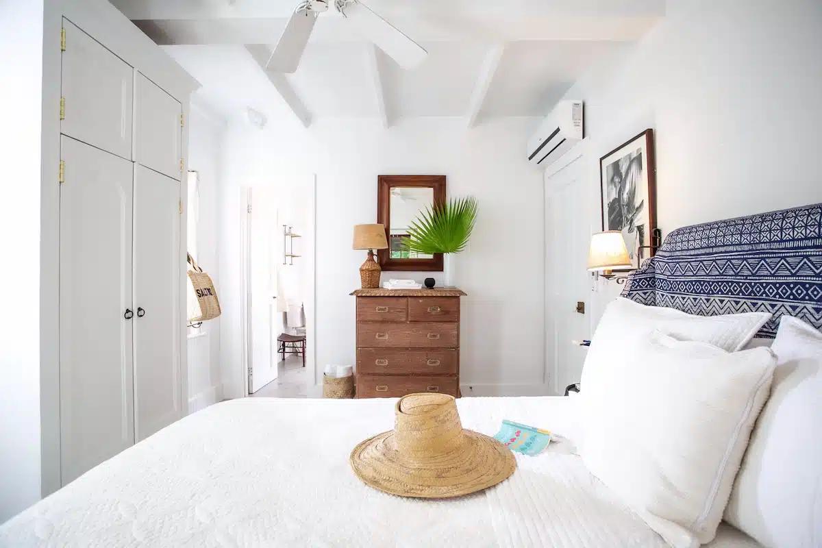 A whitewashed bedroom with a straw hat on the bed