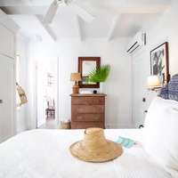 A whitewashed bedroom with a straw hat on the bed