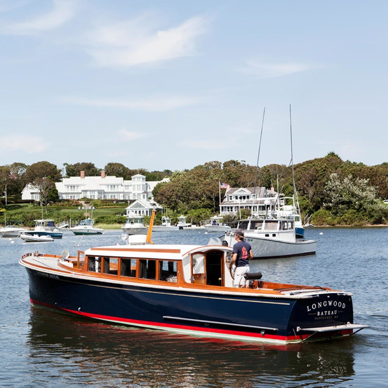 A man sails a boat off the shore in Cape Cod