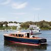 A man sails a boat off the shore in Cape Cod