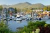 Boats docked at a marina surrounded by green hills.