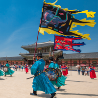 Palace guards at Gyeongbokgung Palace in Seoul parade in bright blue and turquoise robes, carrying colorful shields and flags