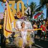 A performer waving a flag walks ahead of a float at the Carnival in Rio de Janeiro, Brazil