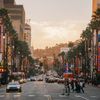 Cars and people crossing the palm-lined Hollywood Boulevard in Los Angeles in golden light