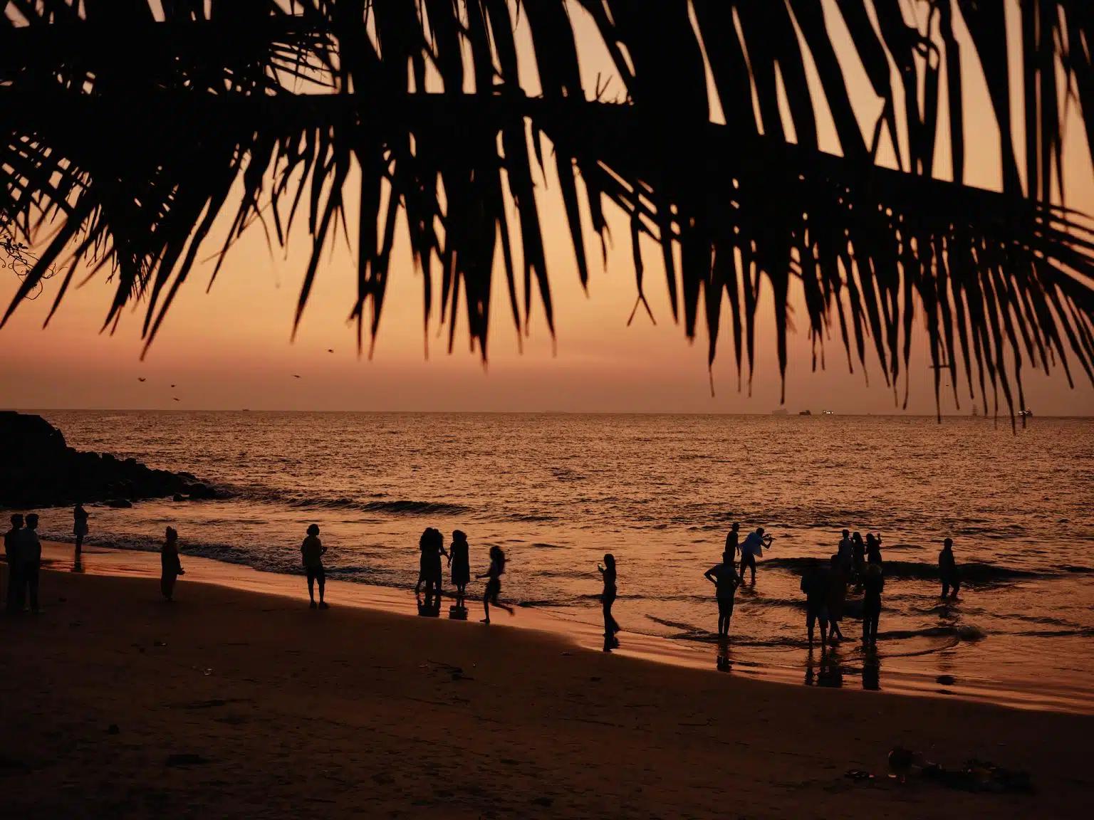 People hang out along the shoreline at sunset on a beach in Kochi, Kerala, India