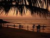 People hang out along the shoreline at sunset on a beach in Kochi, Kerala, India