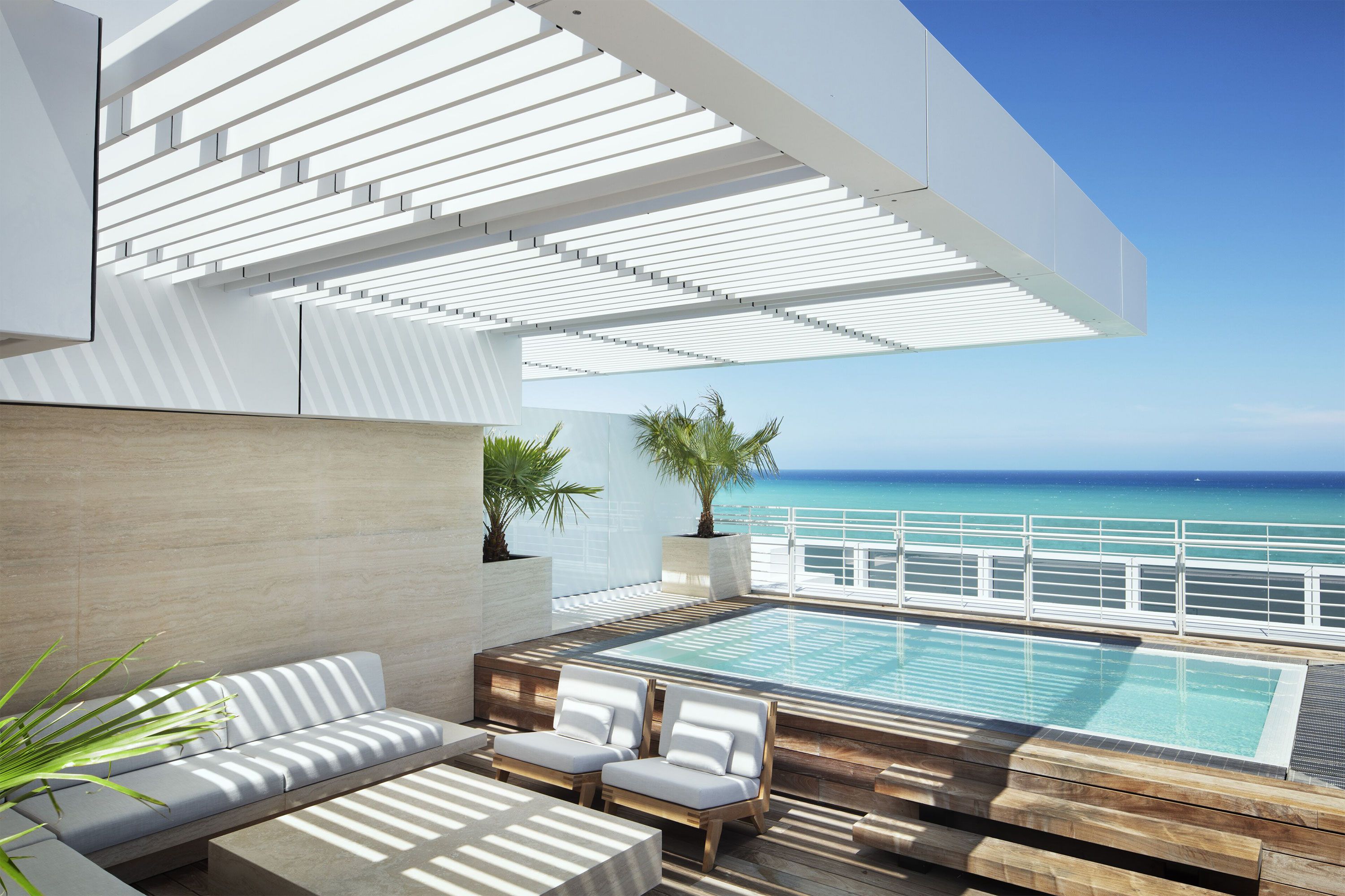 A modern rooftop pool terrace with lounge seating and ocean view.