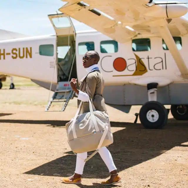 Jessica Nabongo carries a bag to the door of a small shuttle airplane in Tanzania