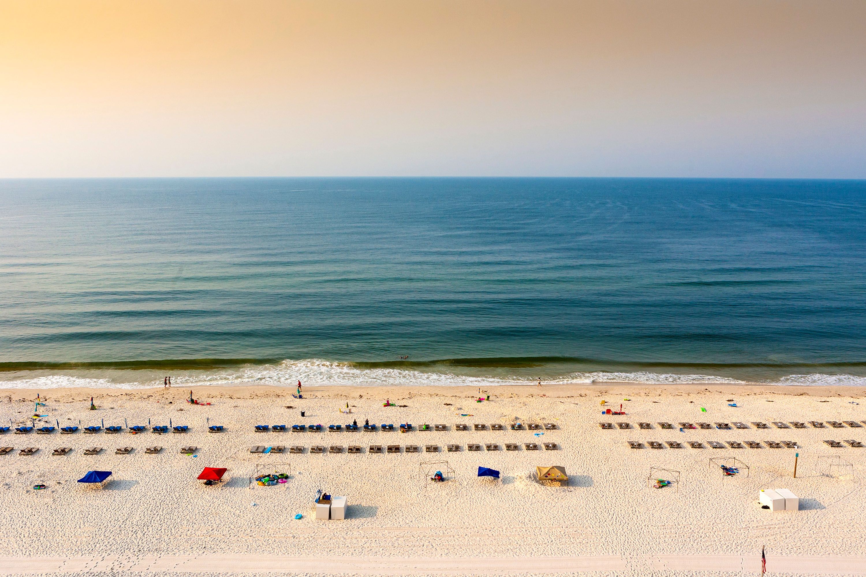 A sandy beach dotted with sun loungers.
