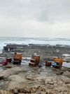 Whisky-barrel seaweed baths sit on the rocky shore in the west of Ireland with an overcast sky